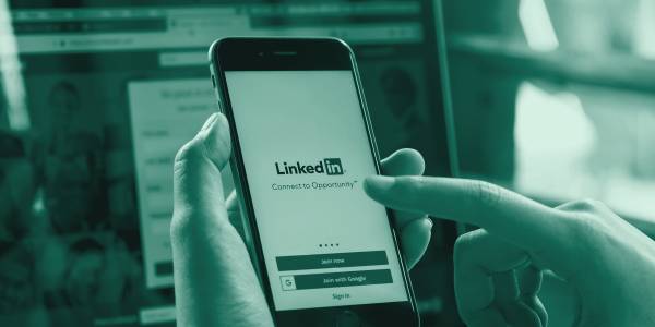 Dłonie z telefonem, otwarta aplikacja LinkedIn